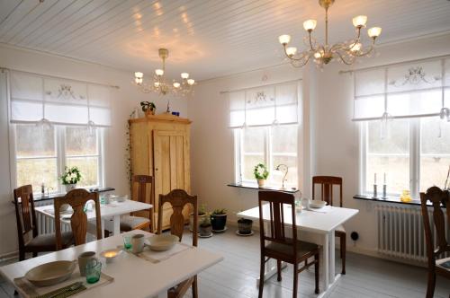 uma sala de jantar com mesas, cadeiras e janelas em Villa Akvarellen Bed & Breakfast em Gerlesborg