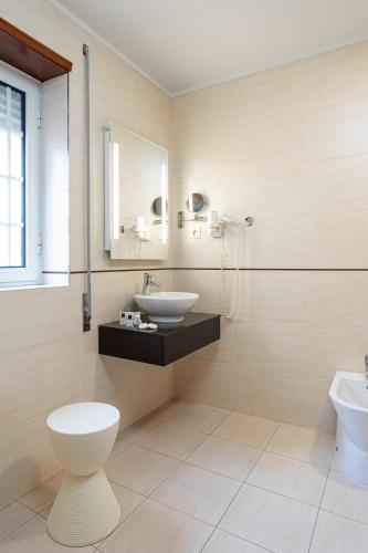 a bathroom with a sink and a toilet and a mirror at Hotel Aveiro Center in Aveiro