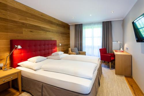 a bedroom with a large bed with a red headboard at Landhotel Gottinger in Waldkirchen