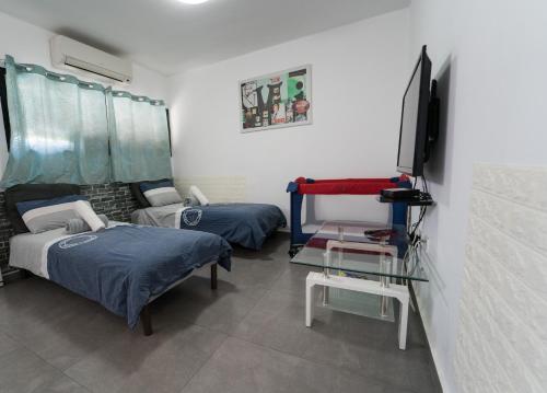 Cette chambre comprend 2 lits, une télévision et une table. dans l'établissement Neviot, à Eilat