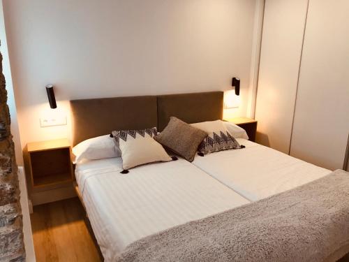 um quarto com uma cama com lençóis brancos e almofadas em Apartamentos Puerto Norte - Apto 2 em Veiga