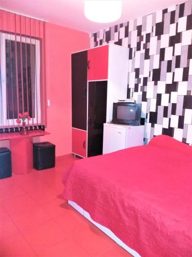 ein rotes Schlafzimmer mit einem Bett und einem TV in der Unterkunft APARTMENT LEO 2 in Warna