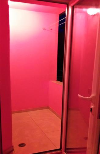 ein Badezimmer mit rosa Wänden und einer Glastür in der Unterkunft APARTMENT LEO 2 in Warna