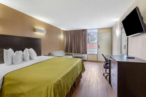 a hotel room with a bed and a flat screen tv at Econo Lodge Roanoke Civic Center in Roanoke