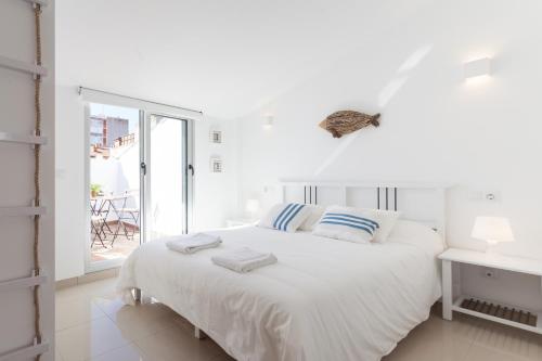 a white bedroom with a white bed and a window at Marina Boutique Duplex in Sant Antoni de Calonge