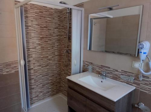 een badkamer met een wastafel en een douche met een spiegel bij Daniela B&B in Cariati