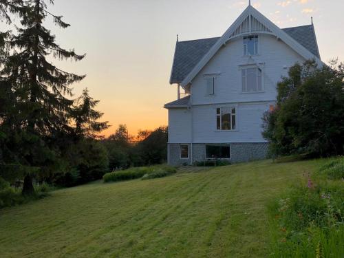 a white house on a grassy hill with the sunset in the background at Arctic Villa Tromsø in Tromsø