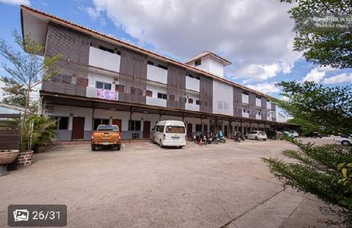un grande edificio con auto parcheggiate in un parcheggio di ลีลาวดีอพาร์ทเมนท์ a Khon Kaen