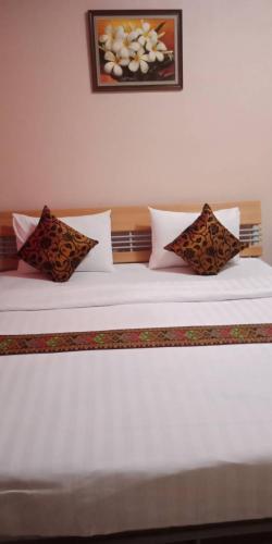 Una cama blanca con varias almohadas. en ลีลาวดีอพาร์ทเมนท์ en Khon Kaen
