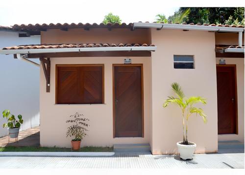 a house with wooden doors and a palm tree in front at Agualinda Hotel in Alter do Chao