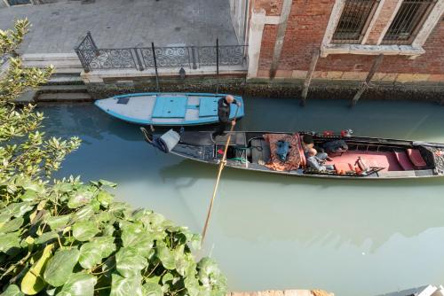 a boat is docked in a river with a person in it at Apartments in San Marco with Canal View in Venice
