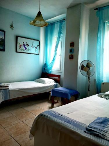 a bedroom with two beds and a window with blue curtains at VILLA TASOS in Iraklitsa