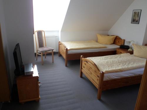 a room with two beds and a tv and a chair at Stadtsee-Pension Templin in Templin