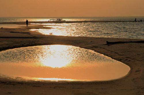 a sunset on the beach with a person in the water at Agualinda Hotel in Alter do Chao