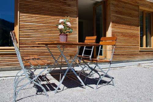 a wooden table with two chairs and a vase with flowers at Spitzing Lodge Ferienwohnungen - Wanderparadies in den Bergen in Spitzingsee