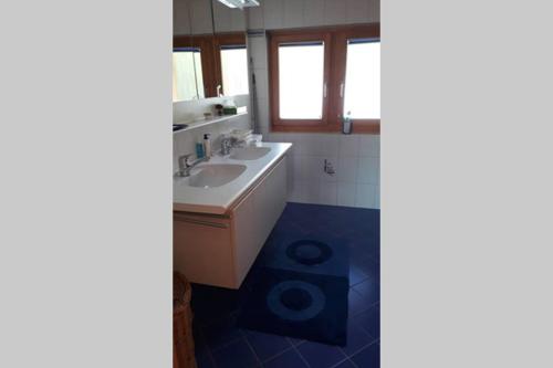 uma casa de banho com um lavatório branco e piso em azulejo azul em Chalet La Marendaz em Ovronnaz