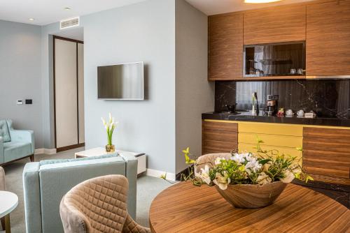a living room with a table and a kitchen at Hotel Pupin Novi Sad in Novi Sad