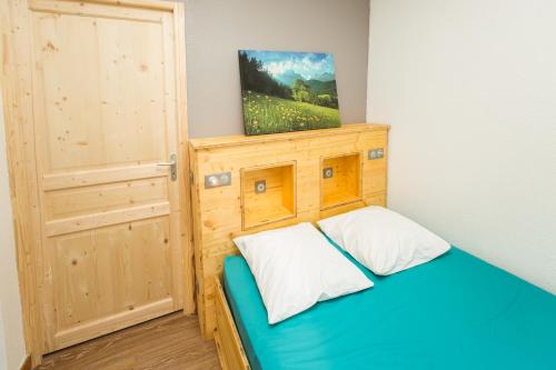 a small bedroom with a wooden bed and a door at Les chalets de Pré Clos en Vercors in Saint-Andéol