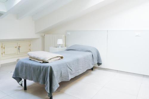 a white bedroom with a bed and a table at LUOGO COMUNE Ostello in Brescia