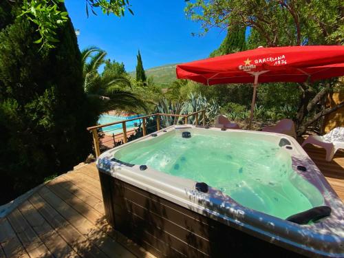 uma banheira de hidromassagem com um guarda-sol no pátio em Camping la Peiriere em Tuchan