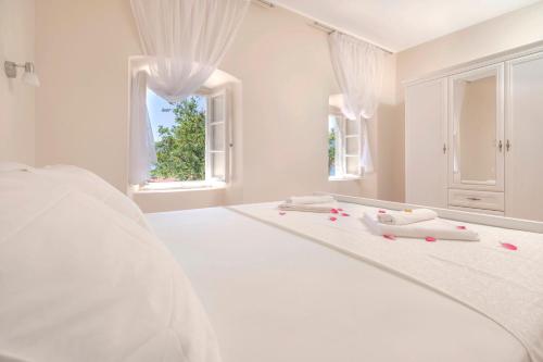 a white bedroom with a large white bed with a window at Old Stone Villa Lalosevic in Kotor