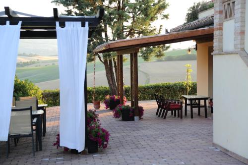 a patio with a white canopy and tables and chairs at Country House Binnella in Cingoli