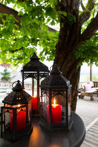 three lanterns with red candles on a table under a tree at Landhotel Gottinger in Waldkirchen