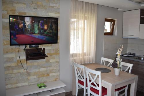 a kitchen with a table and a television on a wall at Apartman G1 u Milmari kompleksu - Kopaonik in Kopaonik