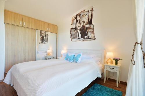 a white bedroom with a large white bed with blue pillows at Egri Otthonom Vendégház in Eger