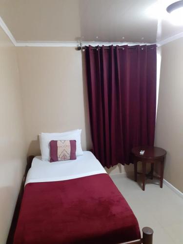a bedroom with a bed with a red curtain at Pista Q hostel and apartments in Oranjestad