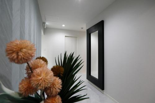 a vase with flowers in a hallway with a mirror at コンドミニアムHARU 那覇県庁前 201 in Naha