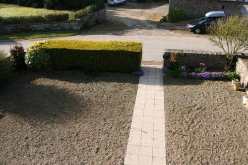 a garden with a hedge and flowers on a sidewalk at Maison de vacances en pierre entre terre et mer in Pluduno