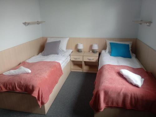 2 łóżka pojedyncze w pokoju z czerwonymi i niebieskimi poduszkami w obiekcie Hostel Załogowa w Gdańsku