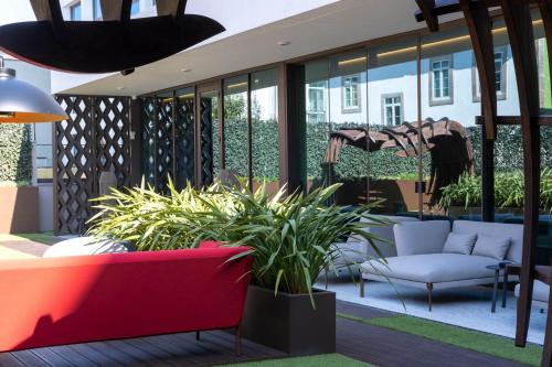 a patio with a red couch and some plants at BessaHotel Baixa in Porto
