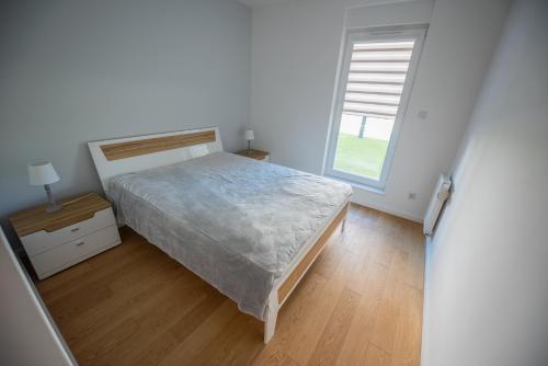a white bedroom with a bed and a window at Apartament nad jeziorem w Iławie- mozliwość wynajęcia motorówki !! in Iława