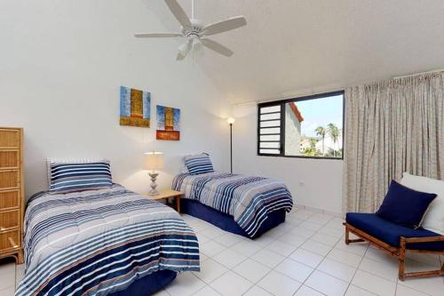 1 dormitorio con 2 camas, silla y ventana en Beach Villa 233, en Humacao