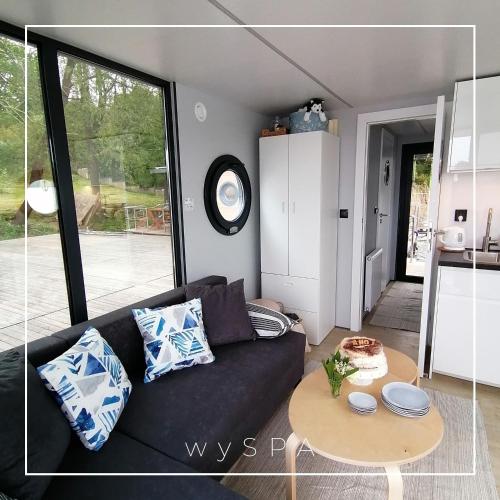 a living room with a black couch and a table at wySPA Kaszuby-domki na wodzie in Ostrzyce