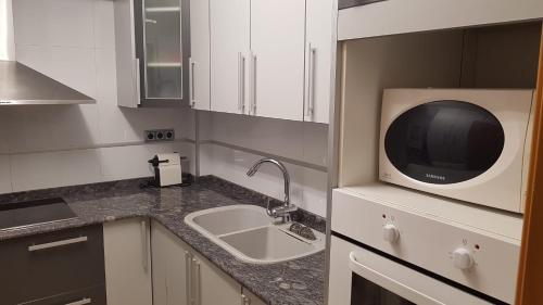 eine Küche mit einer Spüle und einer Mikrowelle in der Unterkunft Apartamento Céntrico in Peñíscola