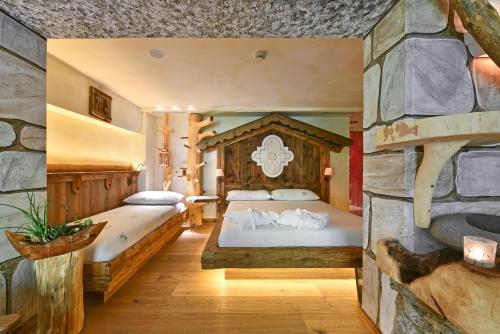 a bedroom with two beds and a stone wall at Hotel Ranuimüllerhof in Villnoss