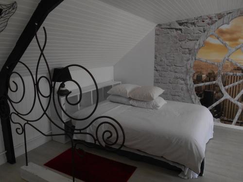 a bedroom with a bed with a stone wall at Au Nid du Thil in Beauvais