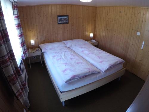 a bed in a room with a wooden wall at Hotel Garni Traube B&B in Schwellbrunn