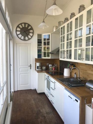 une cuisine avec des placards blancs et une horloge murale dans l'établissement La Fantaisie, à Villers-sur-Mer