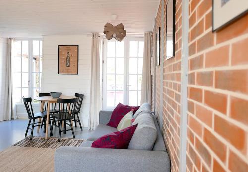 un salon avec un canapé et un mur de briques dans l'établissement Villa de la Plage, la baie du Mont-Saint-Michel, sauna, à Dragey-Ronthon