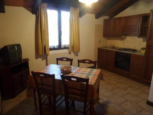 a kitchen with a table and chairs and a television at Al Fogolar in Villa Santina