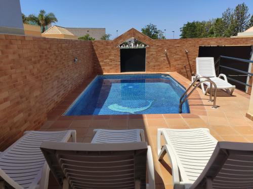 a swimming pool on a patio with chairs and a table at Casa das Figuras in Faro