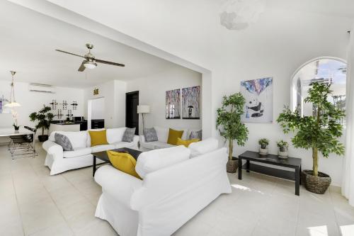 a living room with white furniture and yellow pillows at Flor del Mar Condo Punta Cana Beachfront in Punta Cana