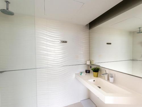 a white bathroom with a sink and a mirror at VacationClub – Ultra Marine Apartament 27 in Kołobrzeg