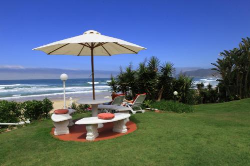 a table and chairs under an umbrella next to the beach at Haus am Strand - on the Beach in Wilderness