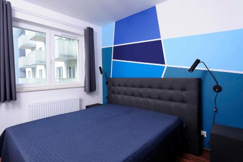 1 dormitorio con cama y pared azul en Sleep Well Inżynierska en Wroclaw