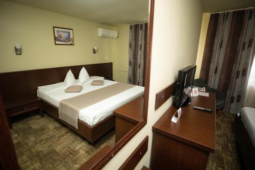 Pokój hotelowy z łóżkiem i lustrem w obiekcie Hotel Select Slobozia w mieście Slobozia